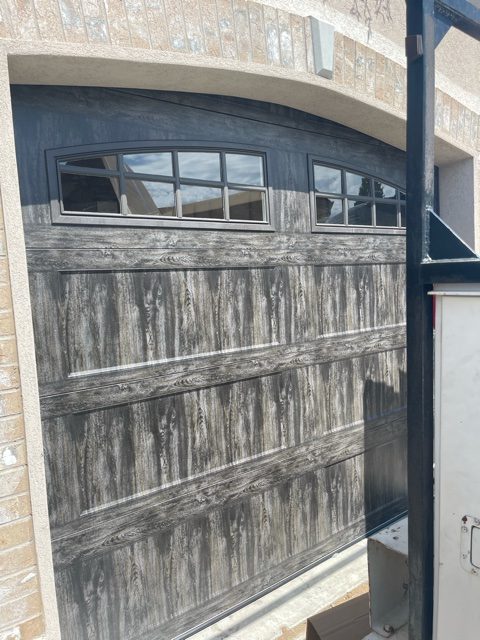 A garage door with wooden paneling, adding a rustic touch to the exterior of a home.