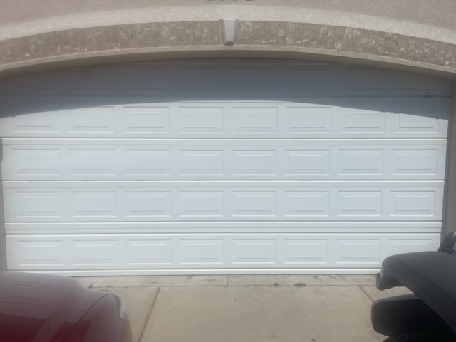 A white garage door against a brick wall, creating a contrasting and visually appealing composition.