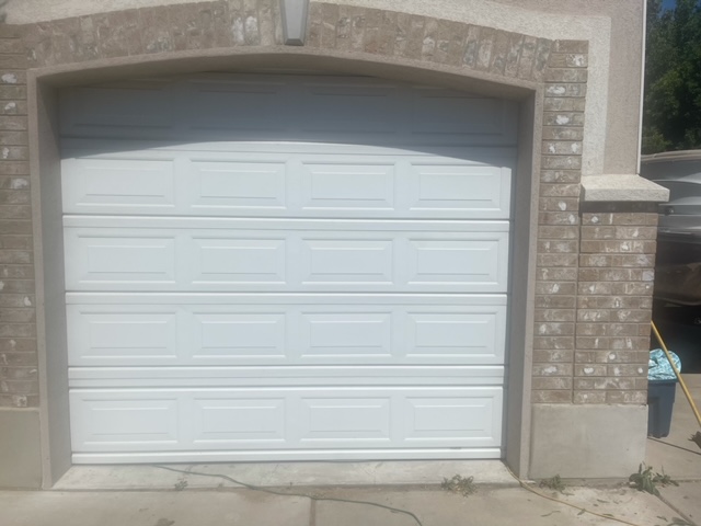 A white garage door against a brick wall, creating a contrasting and visually appealing composition.
