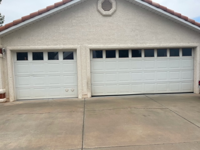 A white garage door with two windows, enhancing the aesthetic appeal of the exterior.