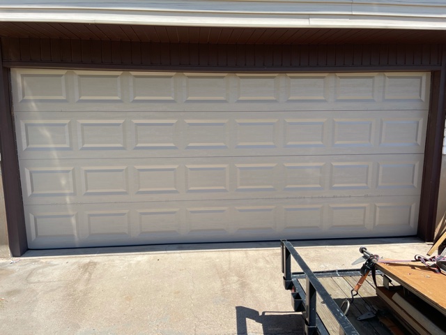 A garage door with a large white door, providing access to a spacious storage area for vehicles and other belongings.