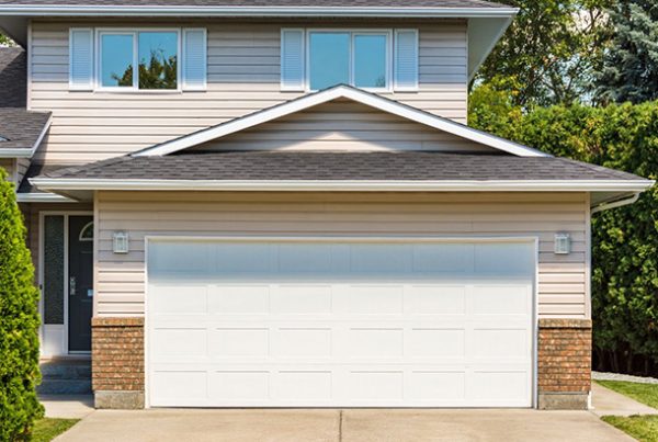 A home with a garage door and a driveway, showcasing the need for garage door replacement.