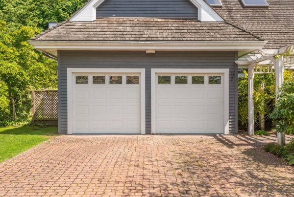 A modern garage with two new insulated garage doors and a pergola.