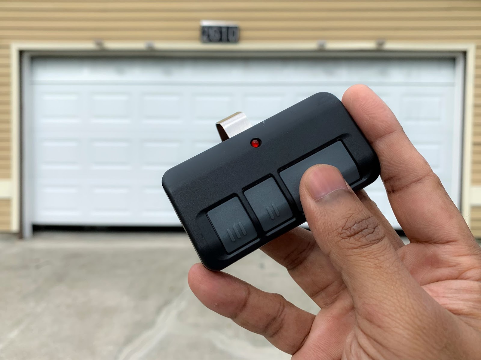 A person using a remote control to operate a functioning garage door, addressing potential garage door issues.