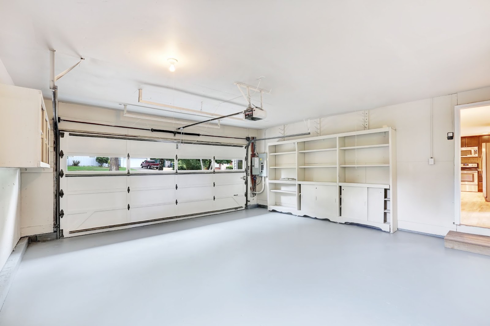 A garage featuring a large white door and organized shelves, ideal for storage and garage door replacement considerations.