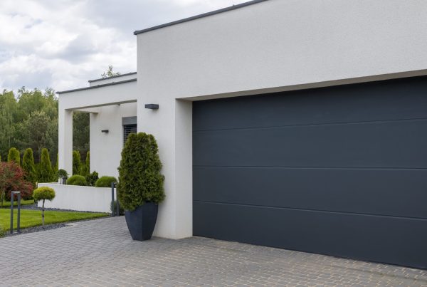 A gray garage door with a planter beside it, illustrating options for garage door replacement and associated costs.