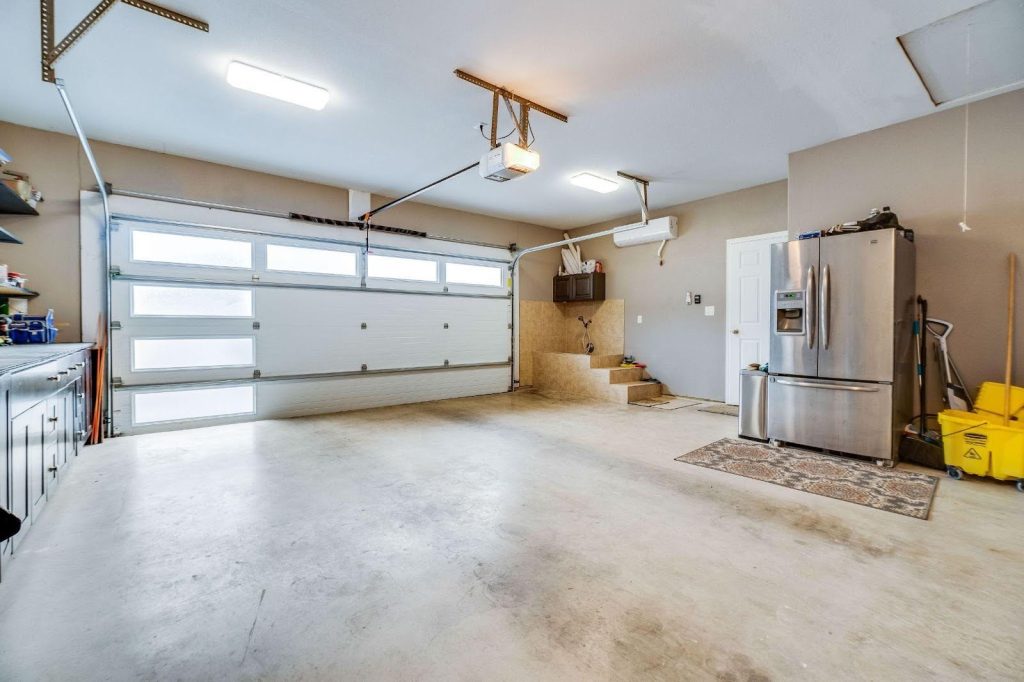 A functional garage with a refrigerator, washer, dryer, and extra fridge