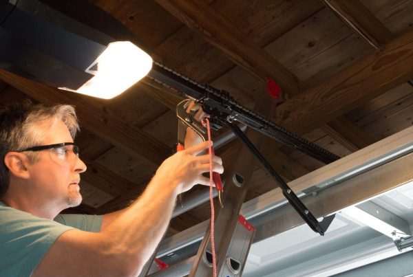 A man skillfully fixes a garage door opener, showing attention to detail