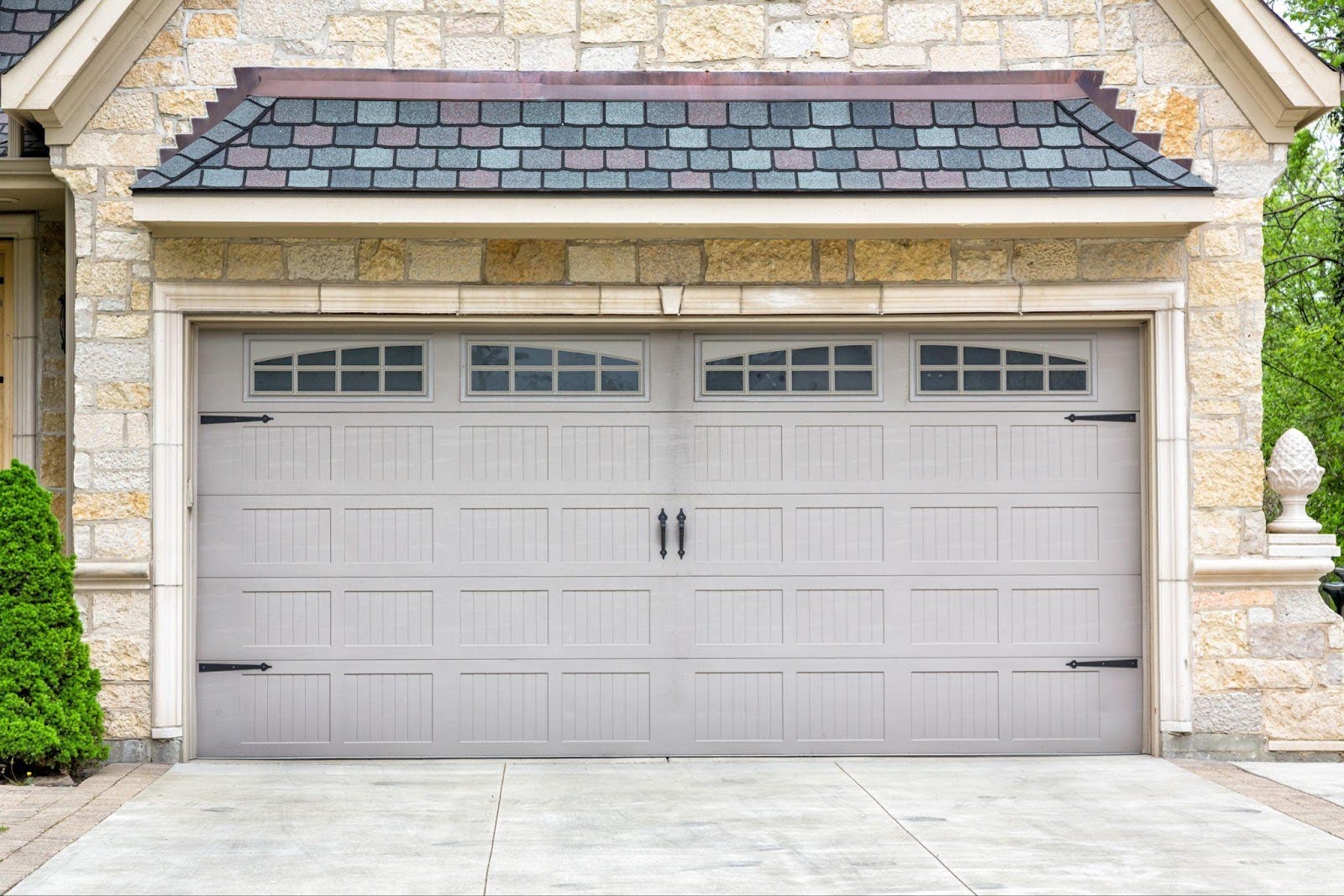 A garage door with two windows against a textured stone wall creates a harmonious design