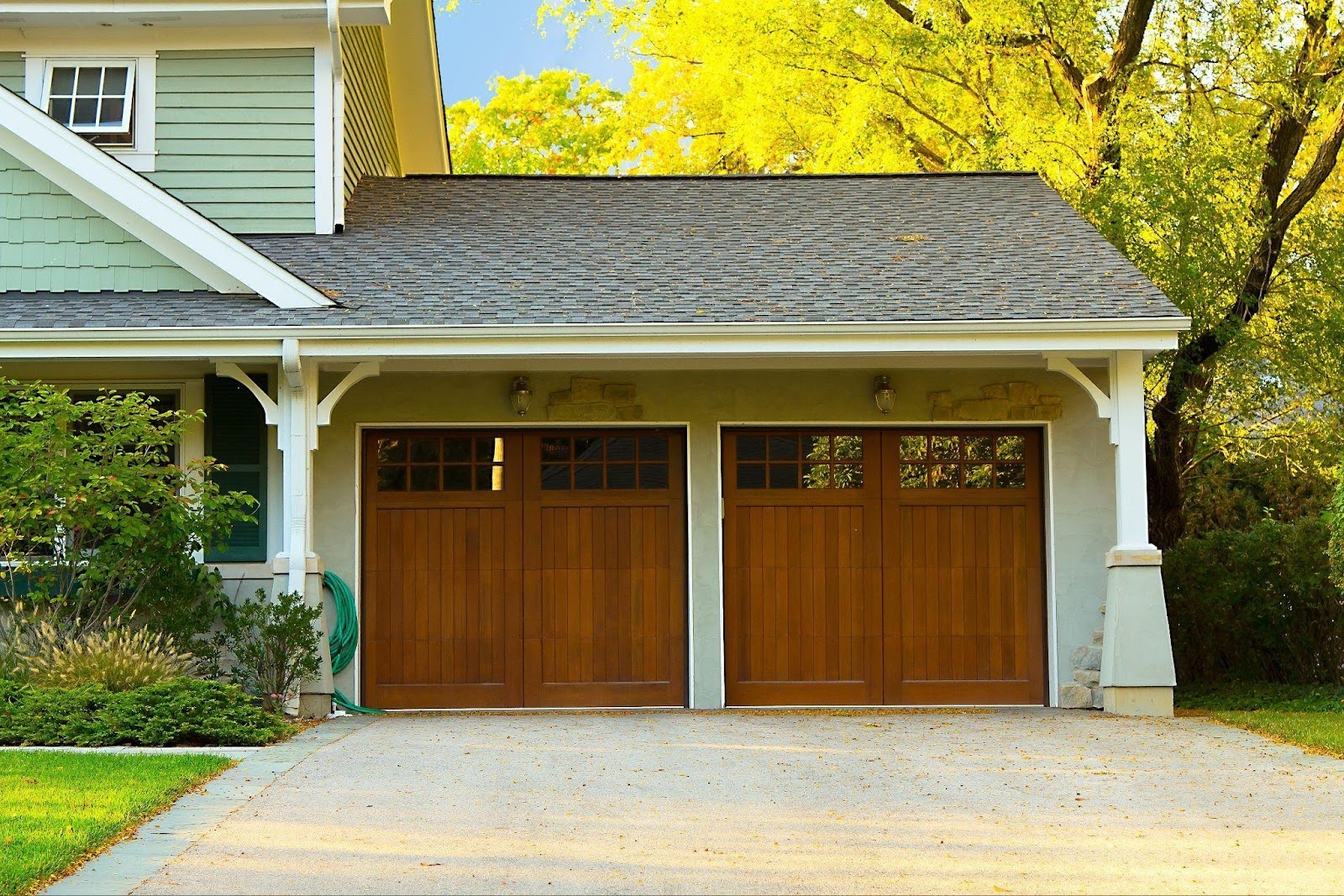 A garage with two wooden doors and a spacious driveway