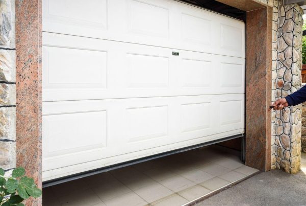 A man confidently stands before a closed garage door, exuding casual poise